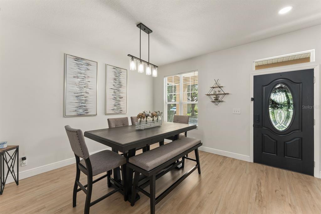 A dining room features a dark wood table with a bench, chairs, and a pendant light — 611 BROOKFIELD TERRACE, DELAND, FL