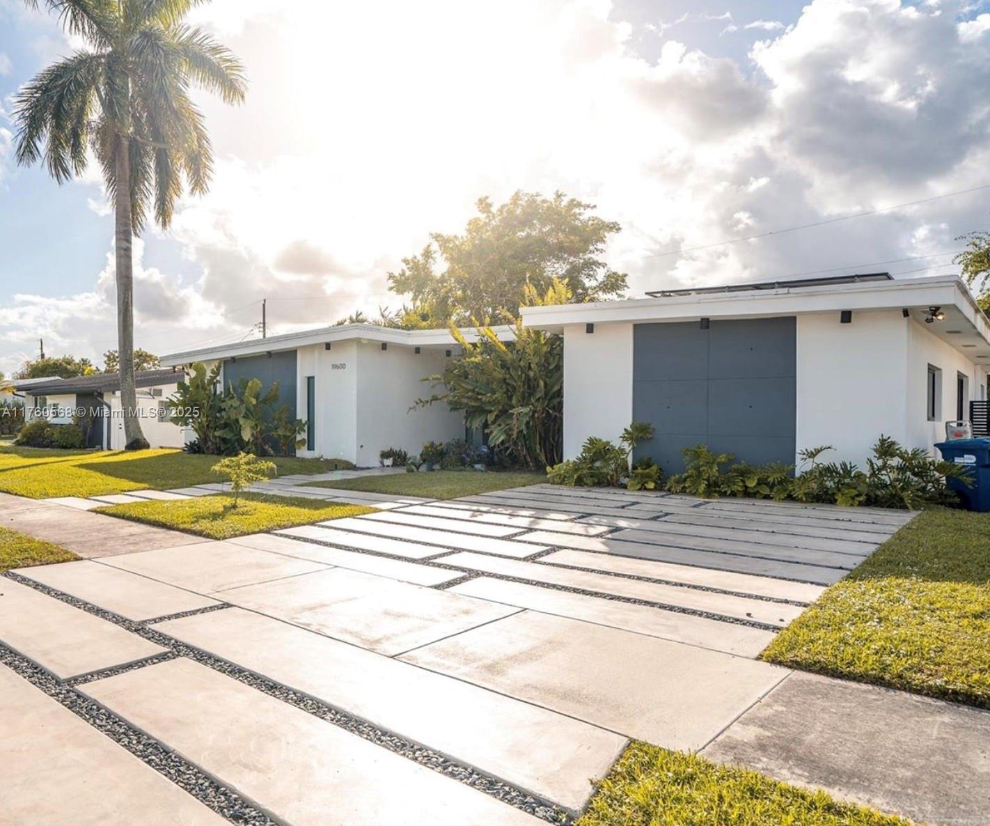 A modern single-story house features a white exterior, a gray garage door, and a paved driveway — 19600 NE 19th Ave, Miami FL 33179, MIAMI, FL