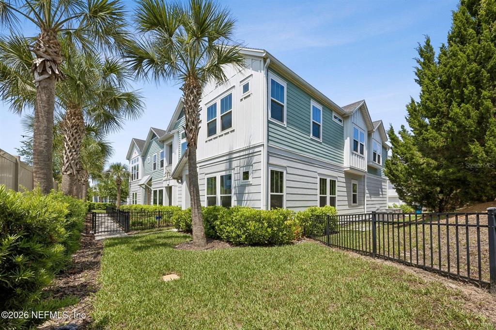 A two-story townhouse with light-colored siding and a black metal fence in the yard — 11496 FATHOM COURT, JACKSONVILLE, FL