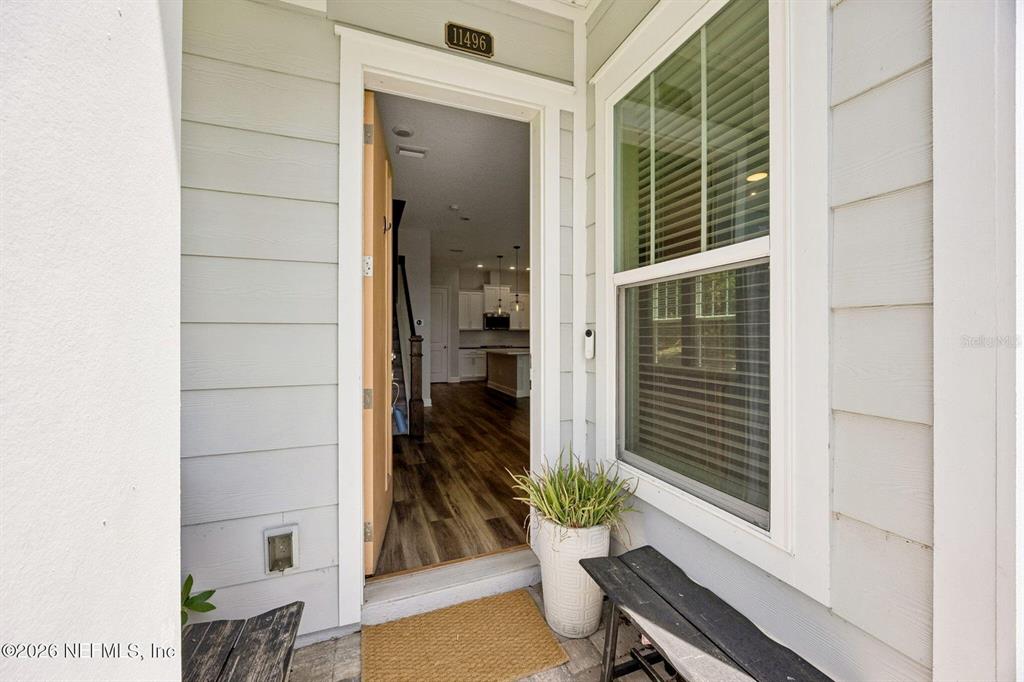 The view from a covered porch looks through an open front door into a home interior — 11496 FATHOM COURT, JACKSONVILLE, FL