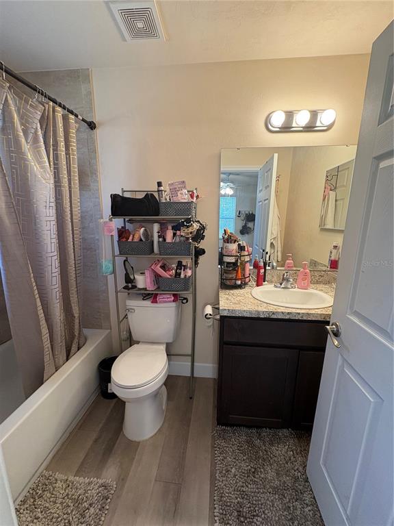 A bathroom features a shower-tub combo, a toilet with an over-the-toilet shelf, and a vanity — 13002 SW 174TH STREET, ARCHER, FL