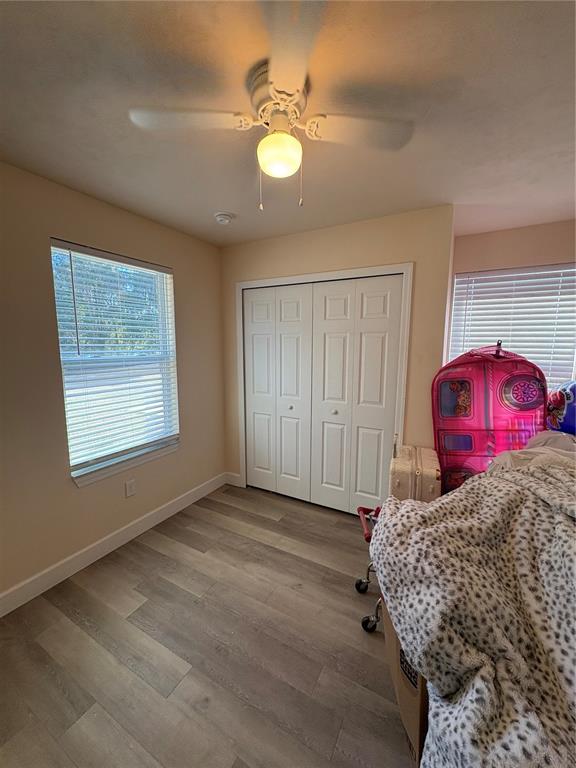 A bedroom with light-colored walls, wood-look flooring, a ceiling fan, and a white closet — 13002 SW 174TH STREET, ARCHER, FL