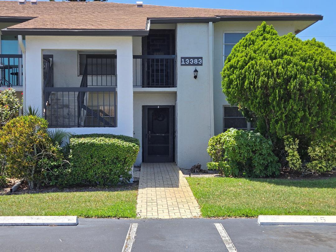 A two-story apartment building exterior features a brick walkway leading to a ground-floor entrance — 13383 Pineapple Palm Court, Delray Beach FL 33484, DELRAY BEACH, FL