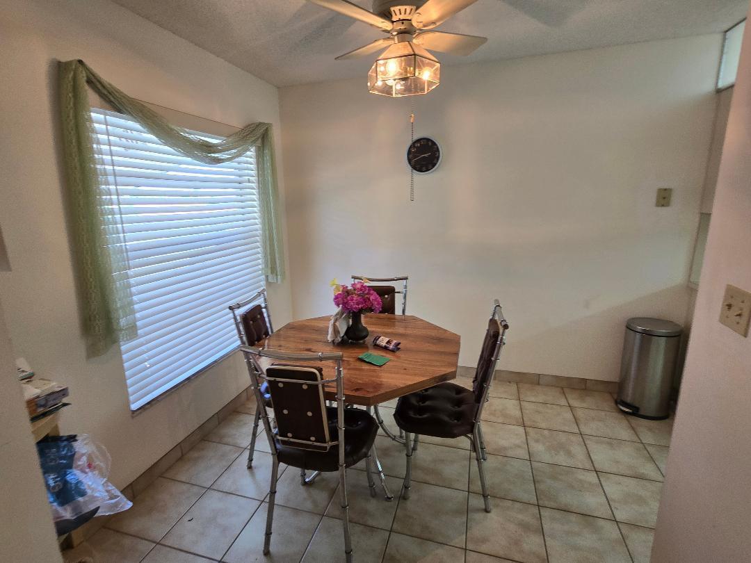 A dining area with an octagonal wooden table, four chairs, tile flooring, and a ceiling fan — 13383 Pineapple Palm Court, Delray Beach FL 33484, DELRAY BEACH, FL