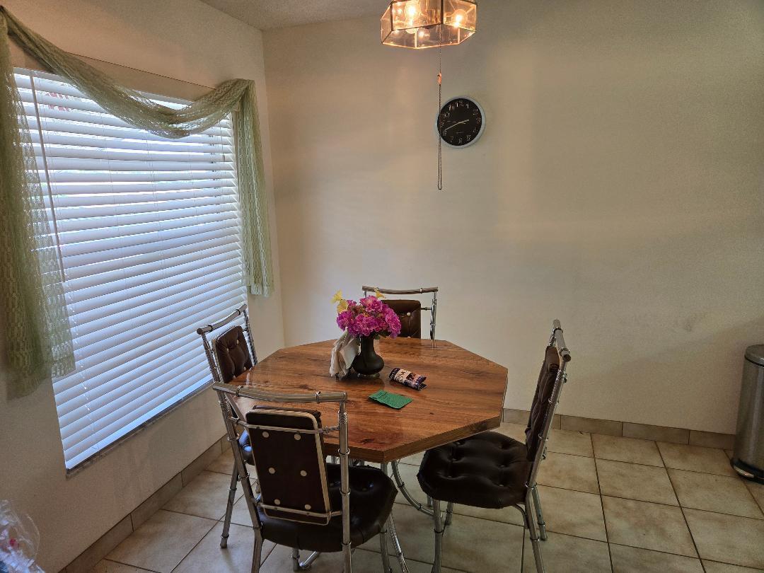 A dining area features an octagonal wooden table, metal chairs, tile flooring, and a window — 13383 Pineapple Palm Court, Delray Beach FL 33484, DELRAY BEACH, FL