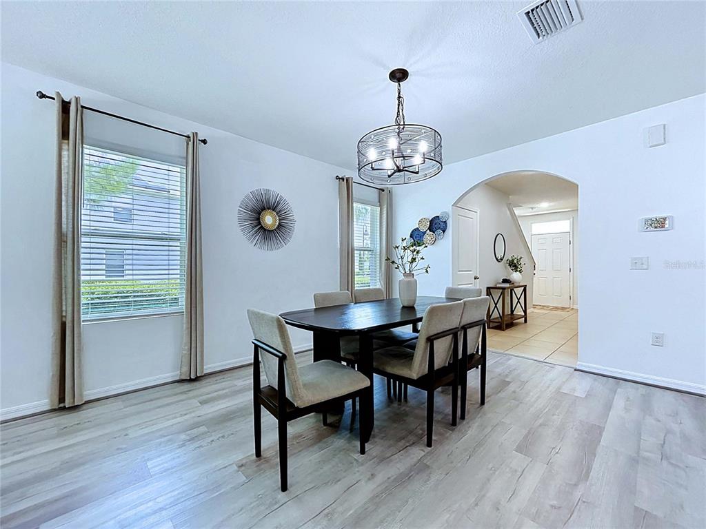 A dining room features a dark wood table, upholstered chairs, a drum chandelier, and light flooring — 16599 SECRET MEADOW DRIVE, ODESSA, FL