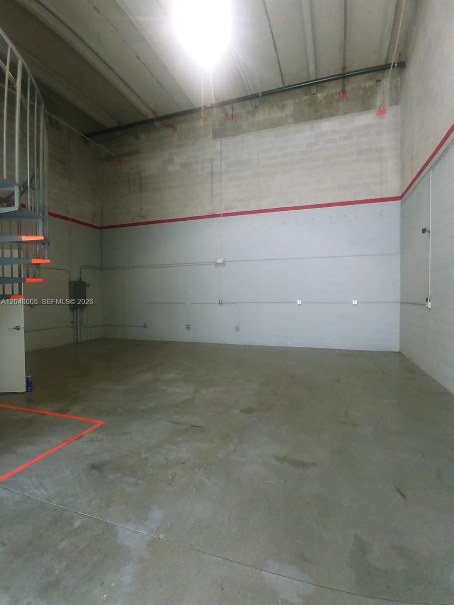 An empty industrial warehouse space features concrete walls, a concrete floor, and a spiral staircase — 2365 NW 70th Ave 18, Miami FL 33122, MIAMI, FL