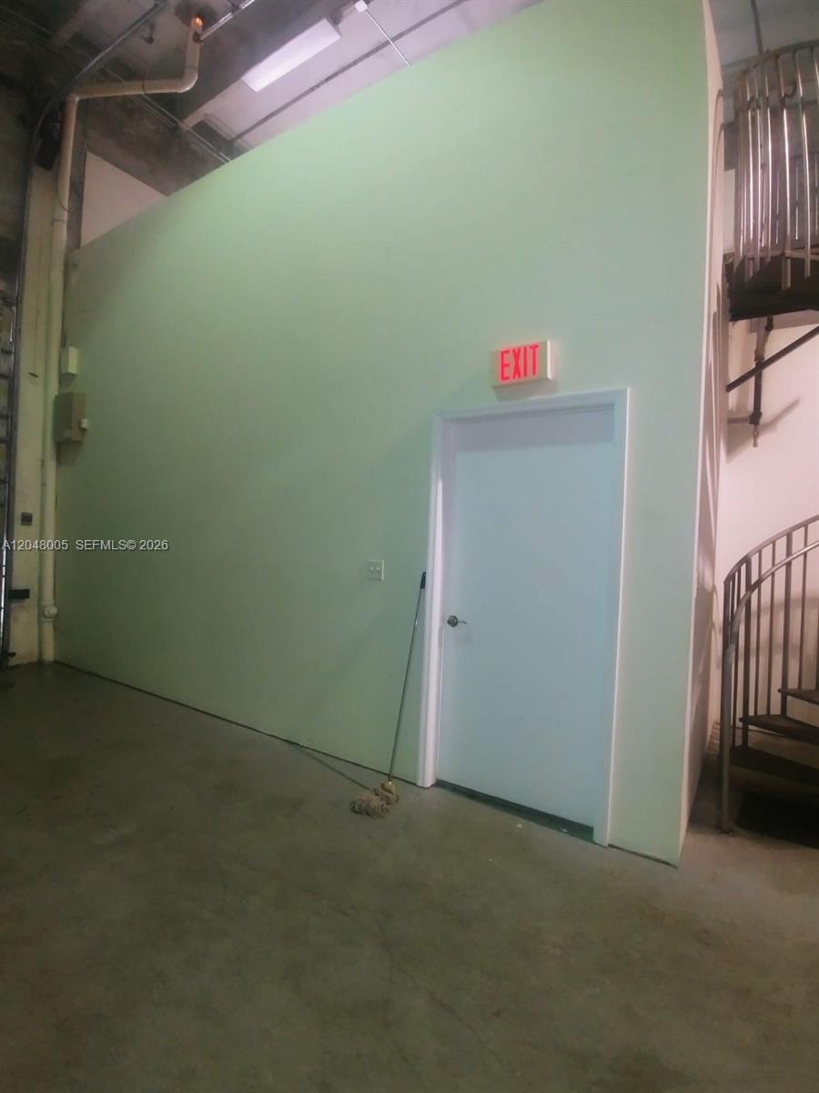A light green wall features an exit door and a nearby spiral staircase — 2365 NW 70th Ave 18, Miami FL 33122, MIAMI, FL