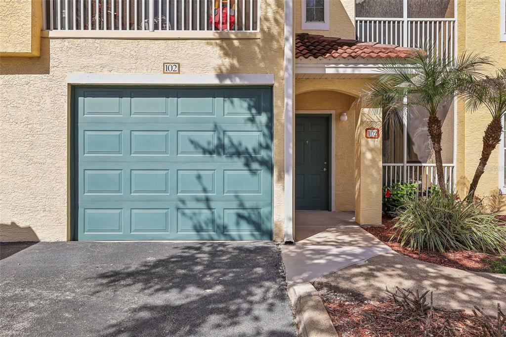 A tan townhouse exterior features a teal garage door, a front entrance, and a palm tree — 12016 VILLANOVA DRIVE UNIT 102, ORLANDO, FL