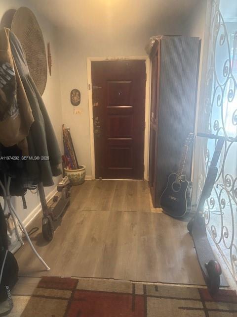 An entryway features wood-look flooring, a dark wooden door, a guitar, and two electric scooters — 15 NE 130th St, North Miami FL 33161, NORTH MIAMI, FL