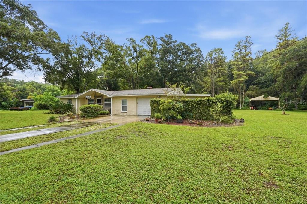 A single-story brick house with a garage and a large lawn surrounded by trees — 3500 OLD KEYSTONE ROAD, TARPON SPRINGS, FL