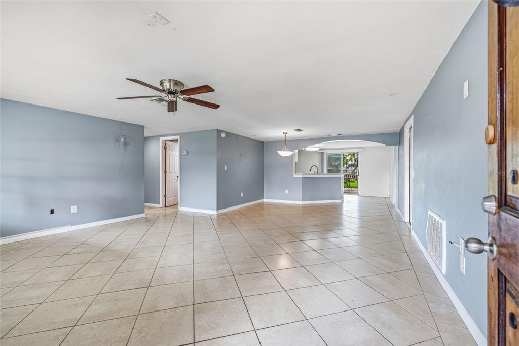 An open-concept living area features light blue walls, tiled floors, and a ceiling fan — 6145 MAPLEWOOD DRIVE, NEW PORT RICHEY, FL