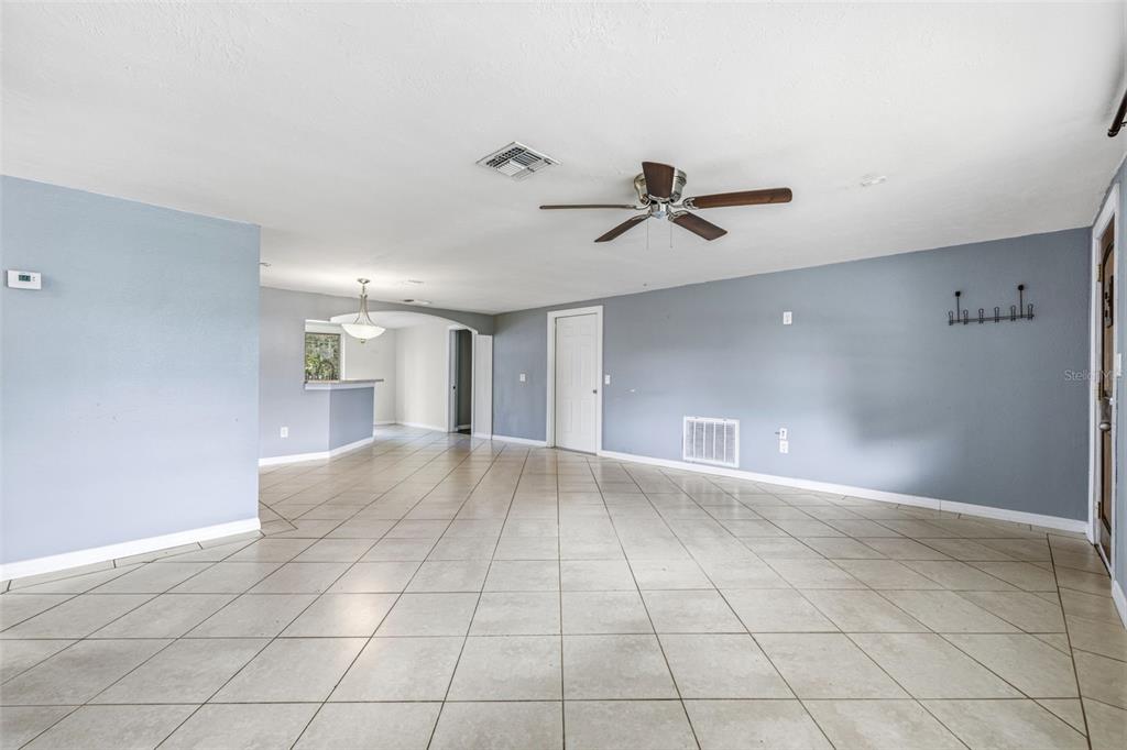 A spacious room with light blue walls, tile flooring, a ceiling fan, and an arched entryway — 6145 MAPLEWOOD DRIVE, NEW PORT RICHEY, FL