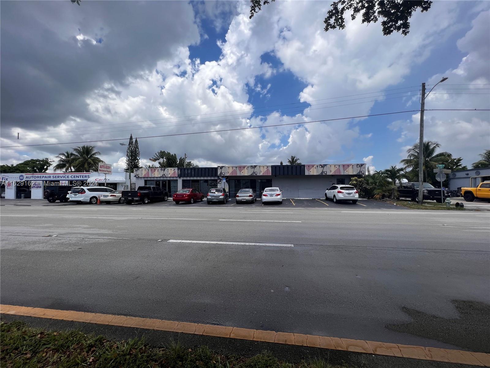 A commercial building with a parking lot and several parked cars under a cloudy sky — 1100 S Dixie Hwy, Hollywood FL 33020, HOLLYWOOD, FL