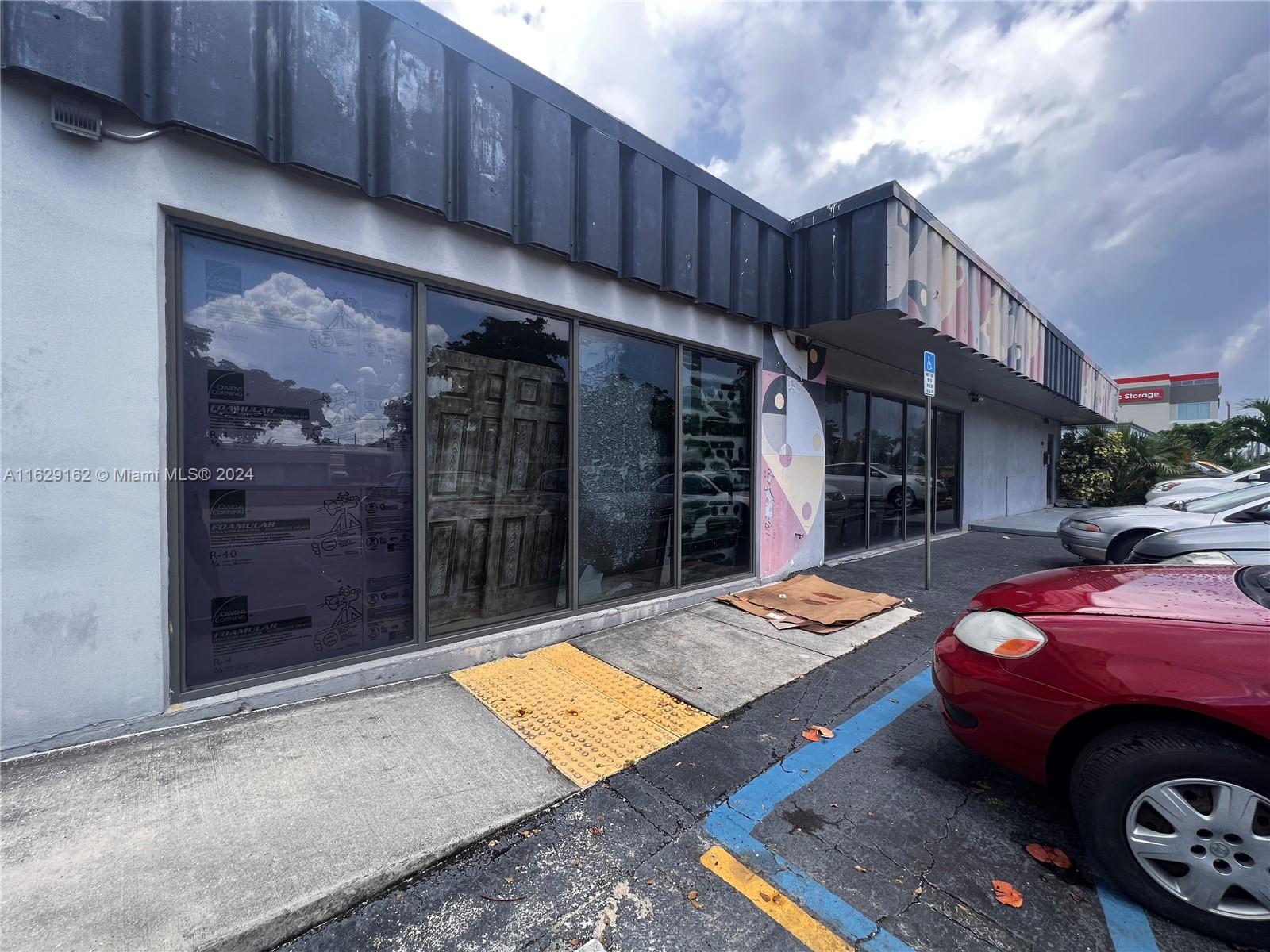 A commercial building exterior features large glass windows, a dark metal awning, and parking spaces — 1100 S Dixie Hwy, Hollywood FL 33020, HOLLYWOOD, FL