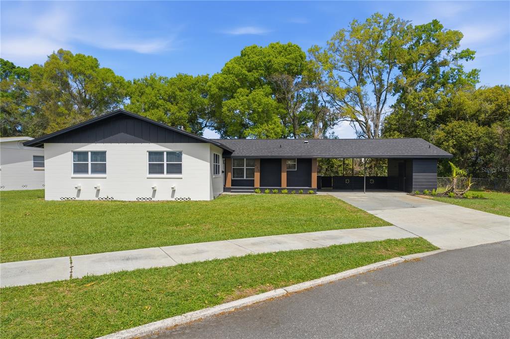 A single-story house with white brick, black trim, and an attached carport under a roof — 405 LAKE FAIR LANE, WINTER PARK, FL