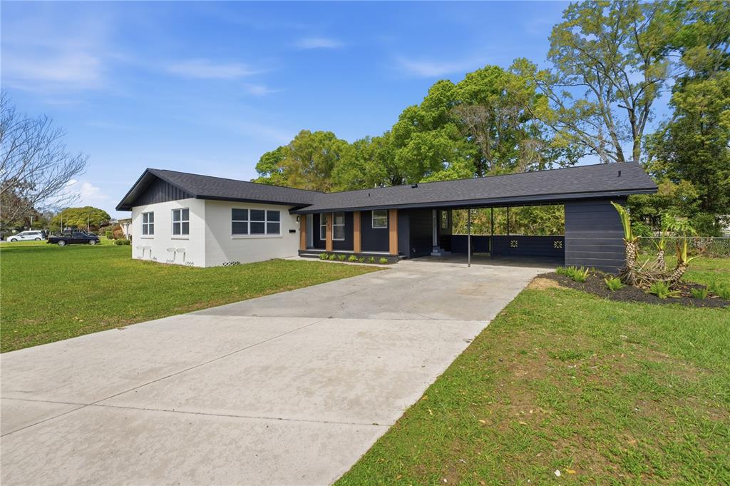 A single-story house with a white brick exterior, dark roof, and an attached carport — 405 LAKE FAIR LANE, WINTER PARK, FL