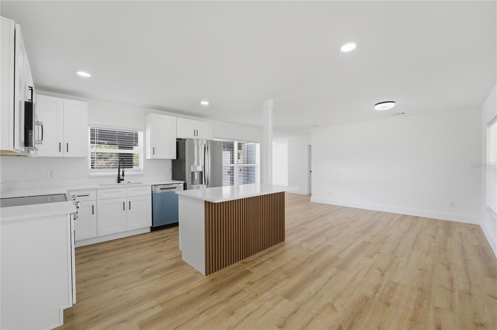 A modern kitchen features white cabinets, a slatted wood island, and light wood-look flooring — 405 LAKE FAIR LANE, WINTER PARK, FL