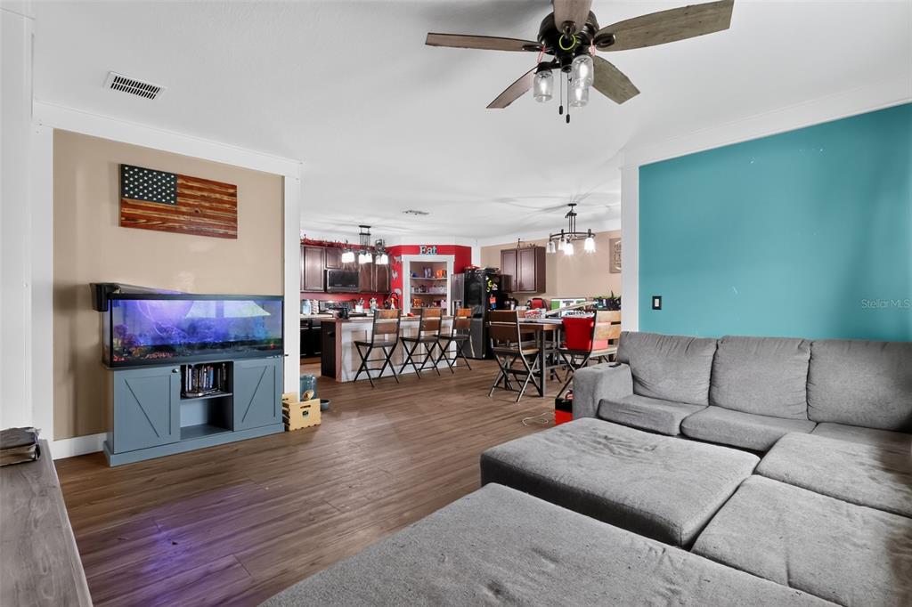 A living room with a gray sectional sofa opens into a kitchen with dark cabinetry — 160 BELLA DRIVE, DAVENPORT, FL