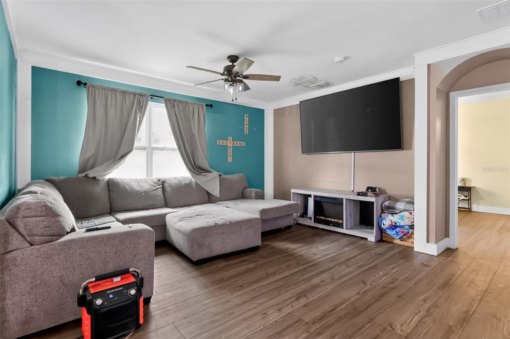 A living room features a gray sectional sofa, a wall-mounted television, and wood-look flooring — 160 BELLA DRIVE, DAVENPORT, FL