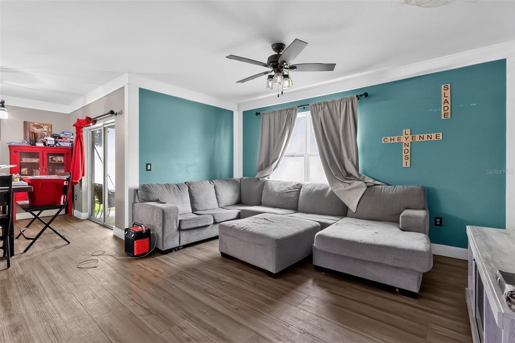 A living room features a gray sectional sofa, teal accent walls, and wood-look flooring — 160 BELLA DRIVE, DAVENPORT, FL