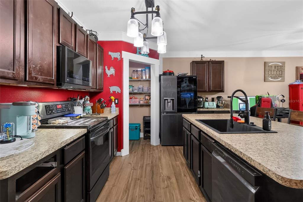 A kitchen features dark wood cabinets, granite countertops, a red accent wall, and a pantry — 160 BELLA DRIVE, DAVENPORT, FL