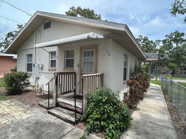 The exterior of a small, light-colored house features a wooden porch and a metal awning — 2534 40TH AVENUE N, ST PETERSBURG, FL