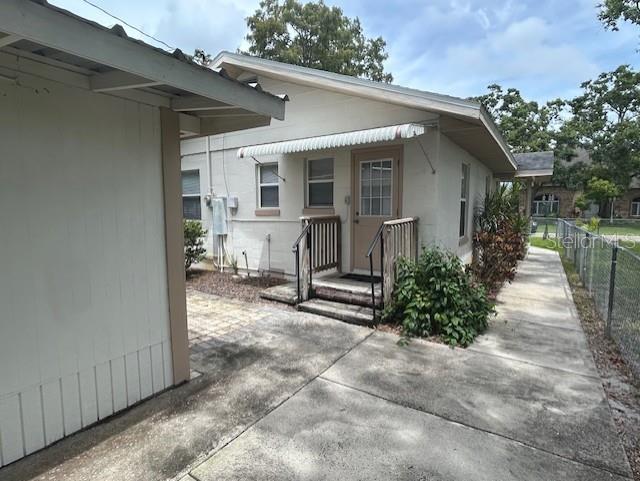 A concrete walkway leads to the side entrance of a light-colored house with an awning — 2534 40TH AVENUE N, ST PETERSBURG, FL