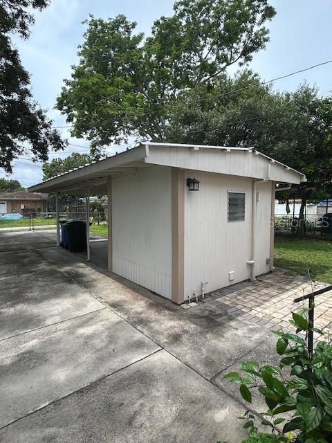 A white detached shed with a covered carport sits on a concrete driveway — 2534 40TH AVENUE N, ST PETERSBURG, FL
