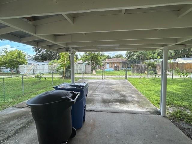 A concrete driveway sits under a covered carport with two large trash bins in front — 2534 40TH AVENUE N, ST PETERSBURG, FL