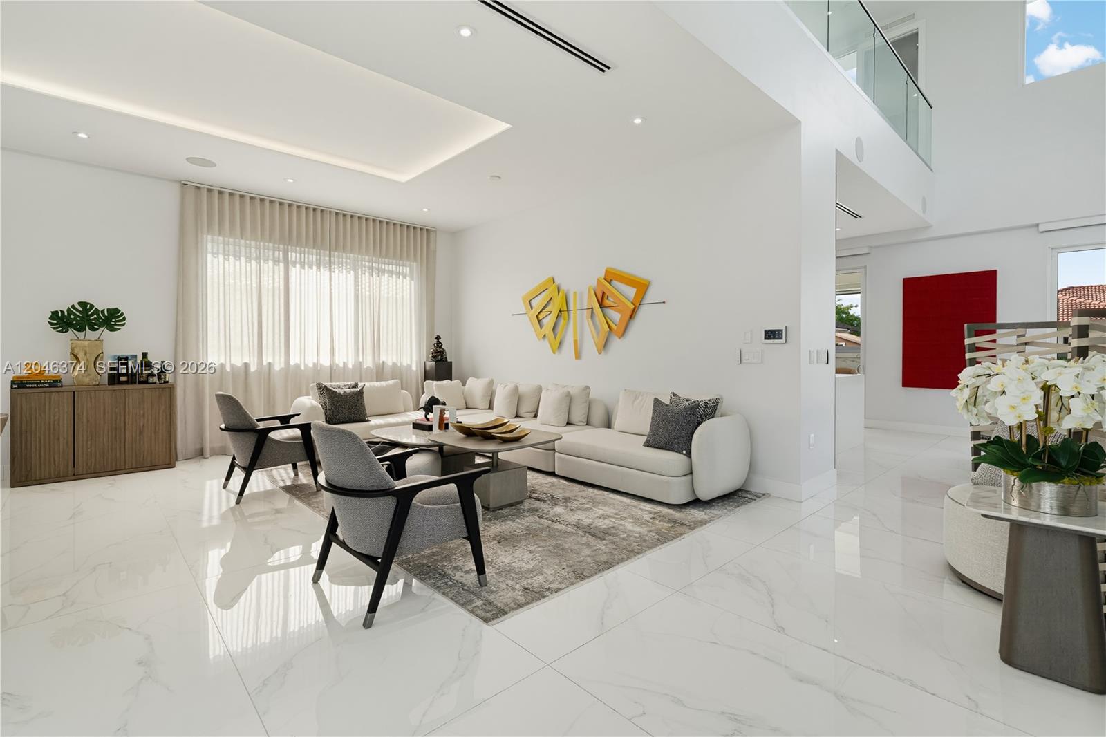 A modern living room features white marble floors, a large sectional sofa, and minimalist decor — DORAL, FL