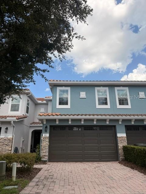 A two-story blue townhouse features a two-car garage and a paved driveway — 1911 SILVERWEED WAY, OVIEDO, FL
