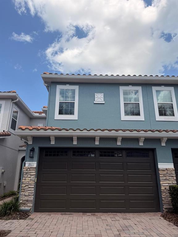 A two-story blue house features a dark brown garage door and stone veneer accents — 1911 SILVERWEED WAY, OVIEDO, FL