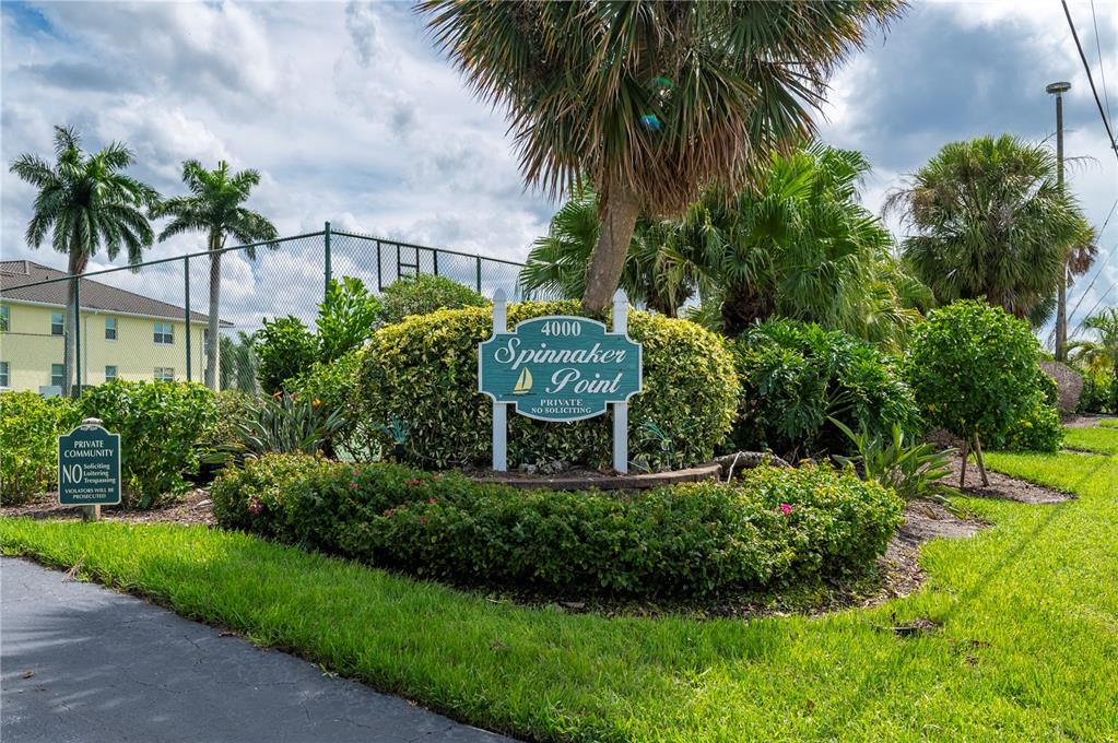 A green sign for Spinnaker Point stands in front of landscaping and a chain-link fence — 4000 BAL HARBOR BOULEVARD UNIT 223, PUNTA GORDA, FL