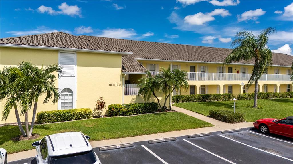 An exterior view of a yellow two-story apartment building with a parking lot in front — 4000 BAL HARBOR BOULEVARD UNIT 223, PUNTA GORDA, FL