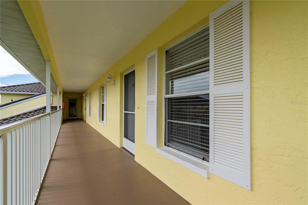 A long, covered outdoor walkway with yellow walls, white railings, and several apartment doors — 4000 BAL HARBOR BOULEVARD UNIT 223, PUNTA GORDA, FL