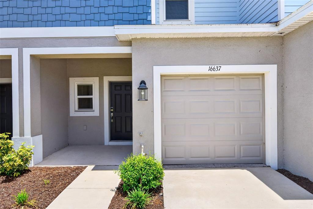 The exterior of a house features a garage, a front door, and a small porch — 16637 BERGAMO PLACE, BRADENTON, FL