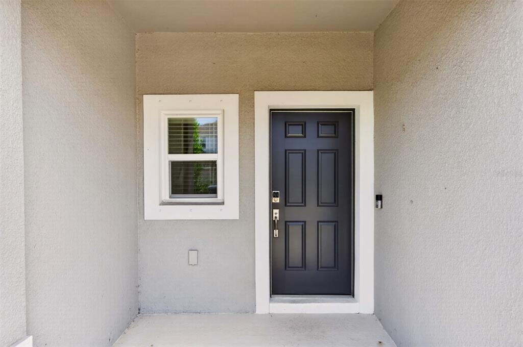 A gray front door and a single window are set into a stucco entryway — 16637 BERGAMO PLACE, BRADENTON, FL