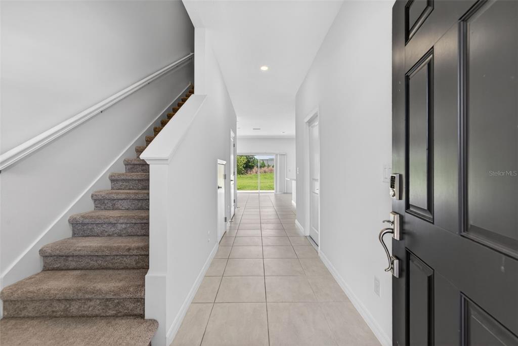 An entryway features a carpeted staircase, tile flooring, and a view toward a rear patio — 16637 BERGAMO PLACE, BRADENTON, FL