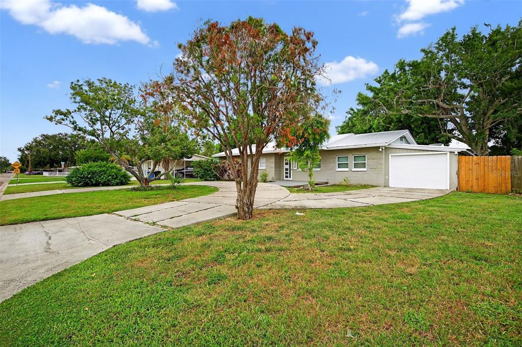 A single-story house with a white garage door, concrete driveway, and trees in the front yard — 300 DAVISON AVENUE NE, ST PETERSBURG, FL