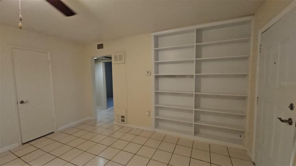 A room with white tile flooring, built-in shelving, and a doorway leading to another area — 21299 COULTON AVENUE, PORT CHARLOTTE, FL