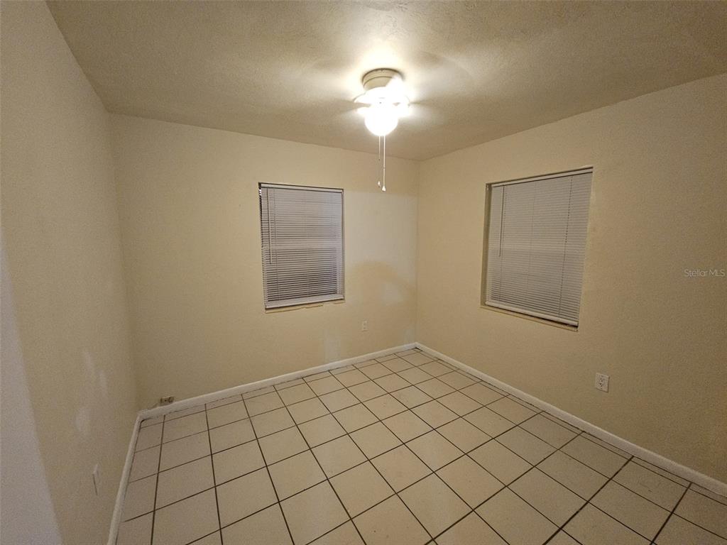 An empty room features beige walls, a ceiling fan, and light-colored square floor tiles — 21299 COULTON AVENUE, PORT CHARLOTTE, FL
