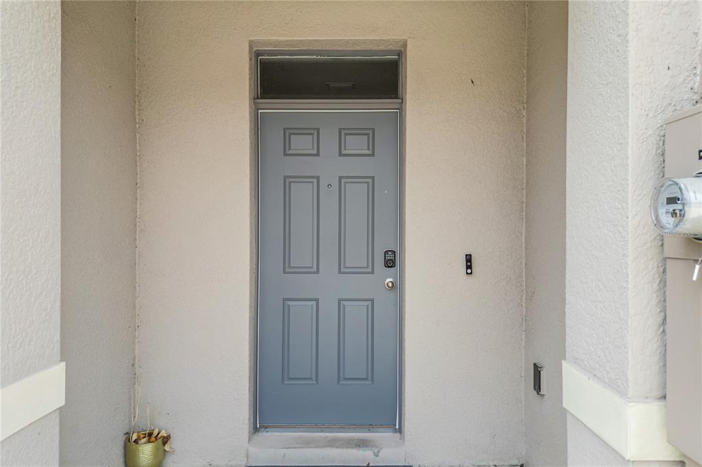 A gray front door with a transom window is set within a beige stucco entryway — 1242 LIDO DRIVE, HOWEY IN THE HILLS, FL