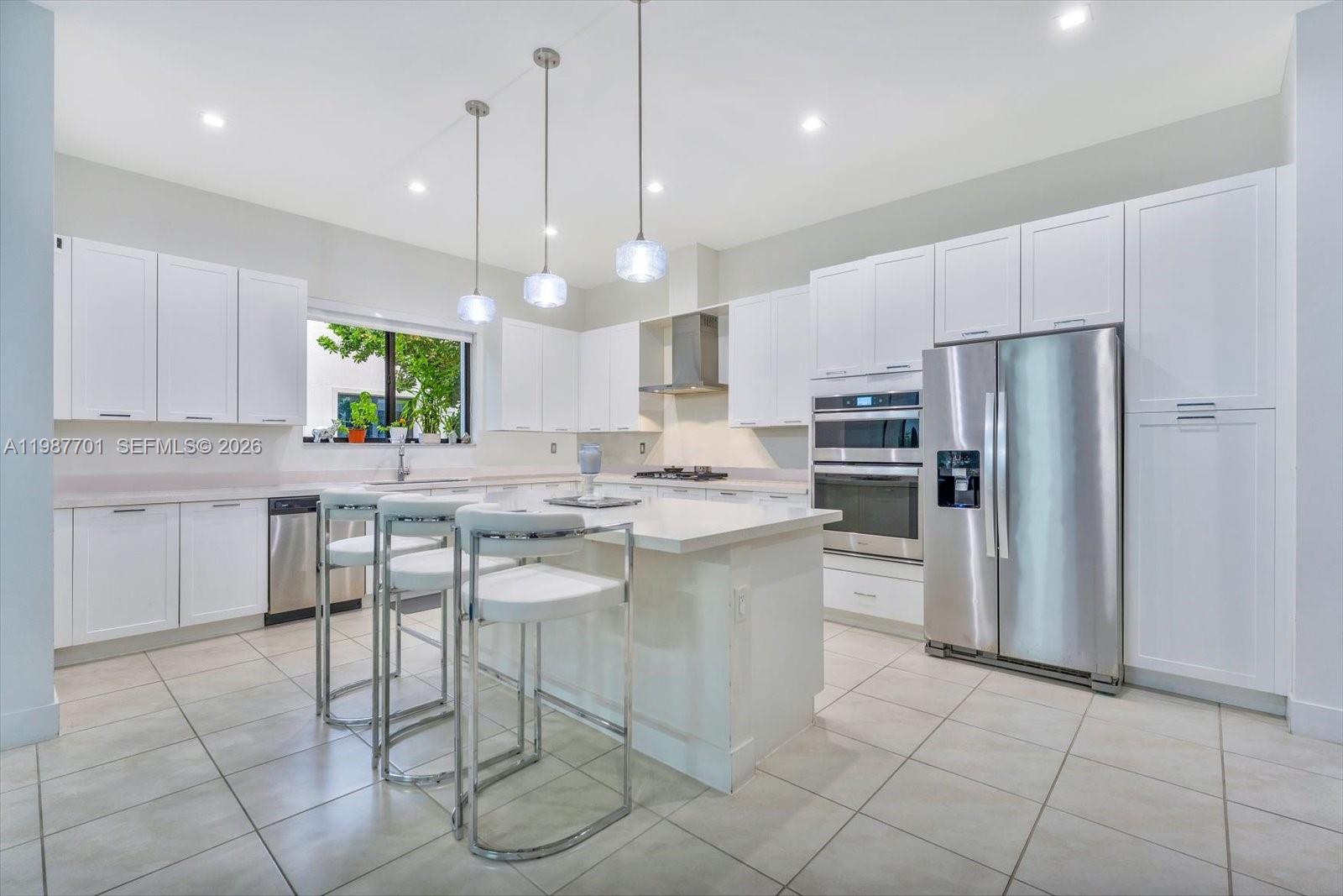 A modern kitchen features white cabinets, stainless steel appliances, a center island, and tile flooring — 4346 NW 81st Ave, Doral FL 33166, DORAL, FL