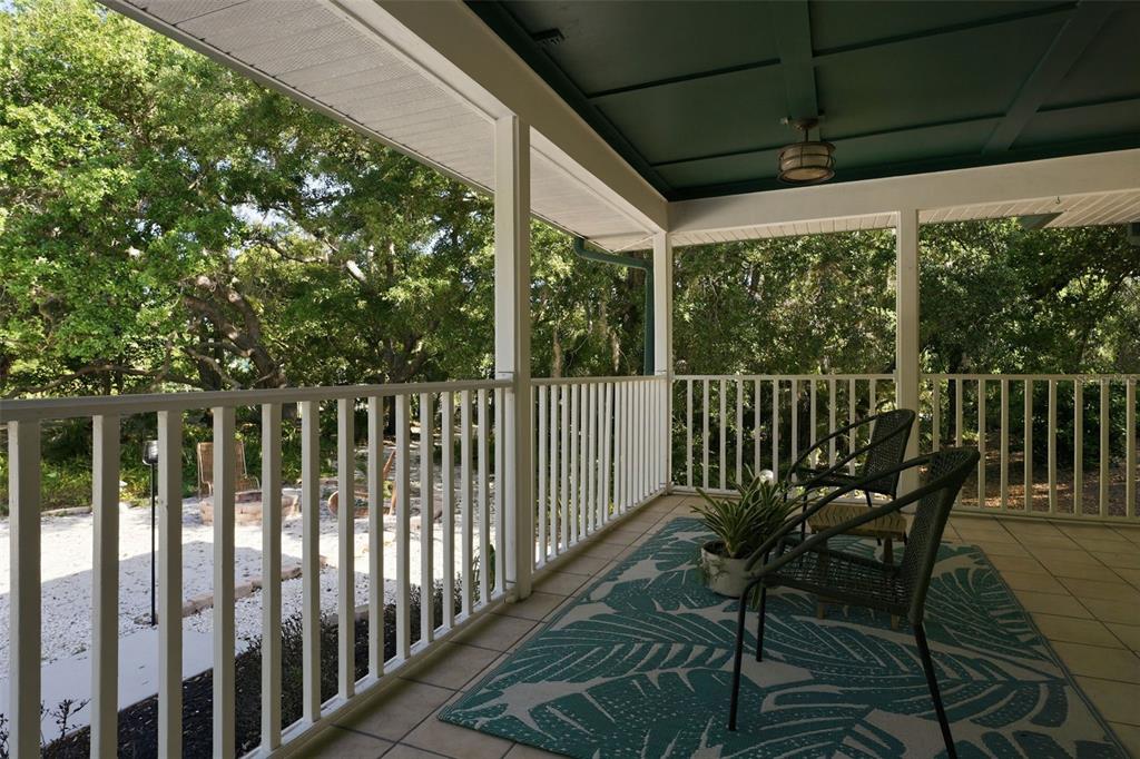 A covered porch features a white railing, tile flooring, a patterned rug, and outdoor seating — 5438 COLD SPRING LANE, NORTH PORT, FL