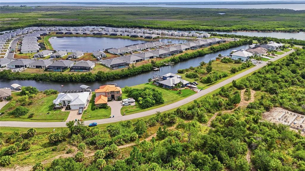 An aerial view shows waterfront houses with pools and boat docks in a suburban community — 15484 MARGO CIRCLE, PORT CHARLOTTE, FL