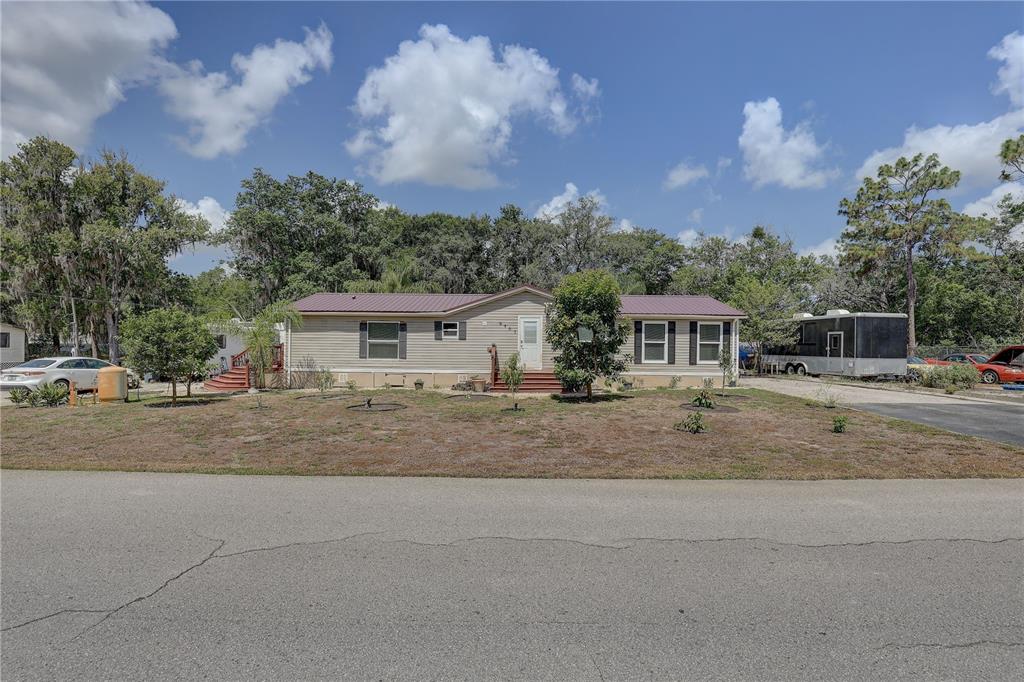 A single-story manufactured home with light siding and a metal roof sits on a lot — 9501 ESTELLE STREET, NEW PORT RICHEY, FL
