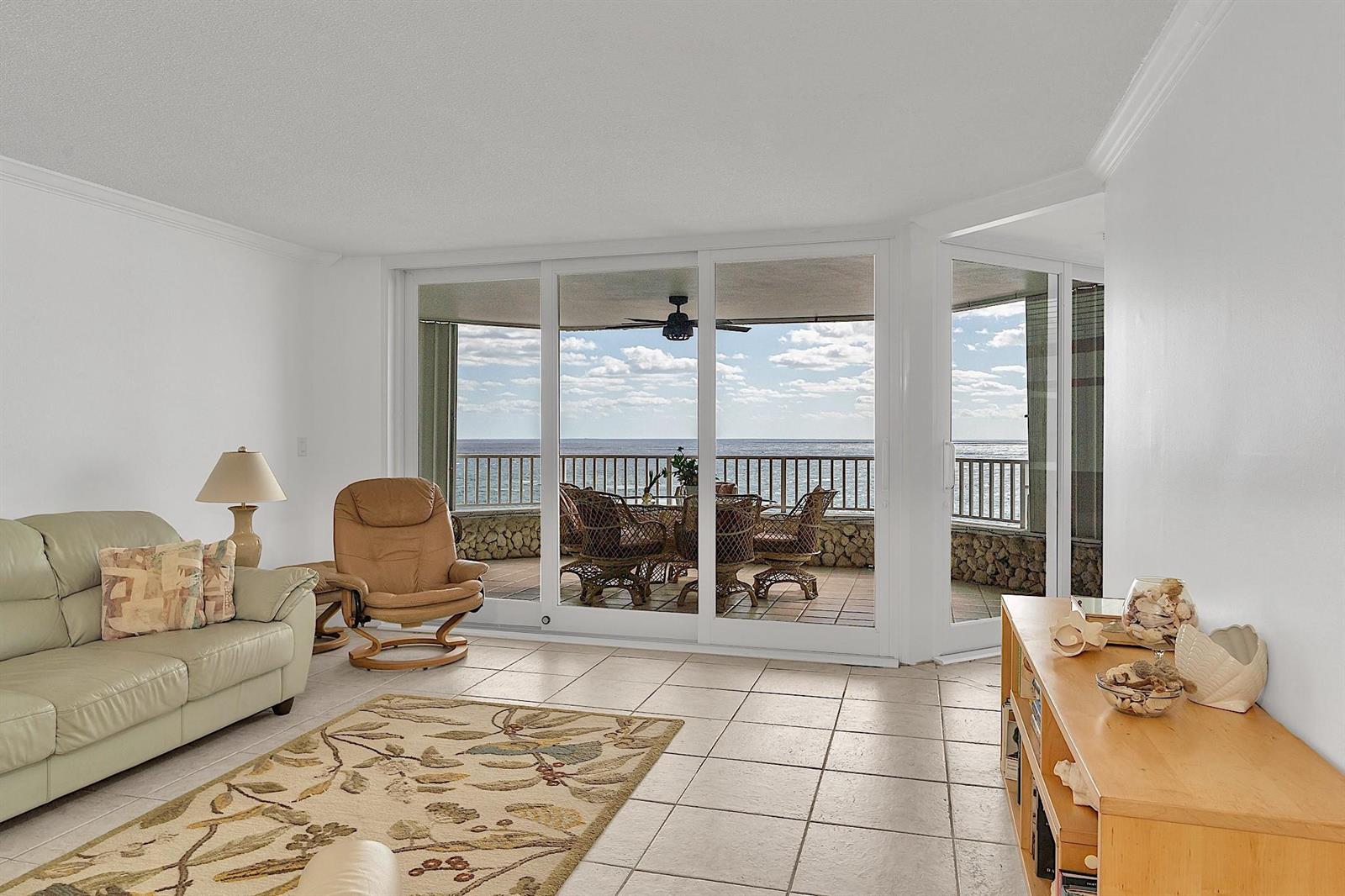 A living room with tile floors, a beige sofa, and sliding glass doors overlooking the ocean — 1340 S Ocean Boulevard # 1106, Pompano Beach FL 33062, POMPANO BEACH, FL