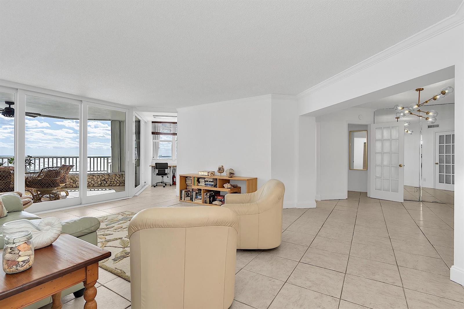 A bright living room with tile floors, beige armchairs, and a view of the ocean — 1340 S Ocean Boulevard # 1106, Pompano Beach FL 33062, POMPANO BEACH, FL