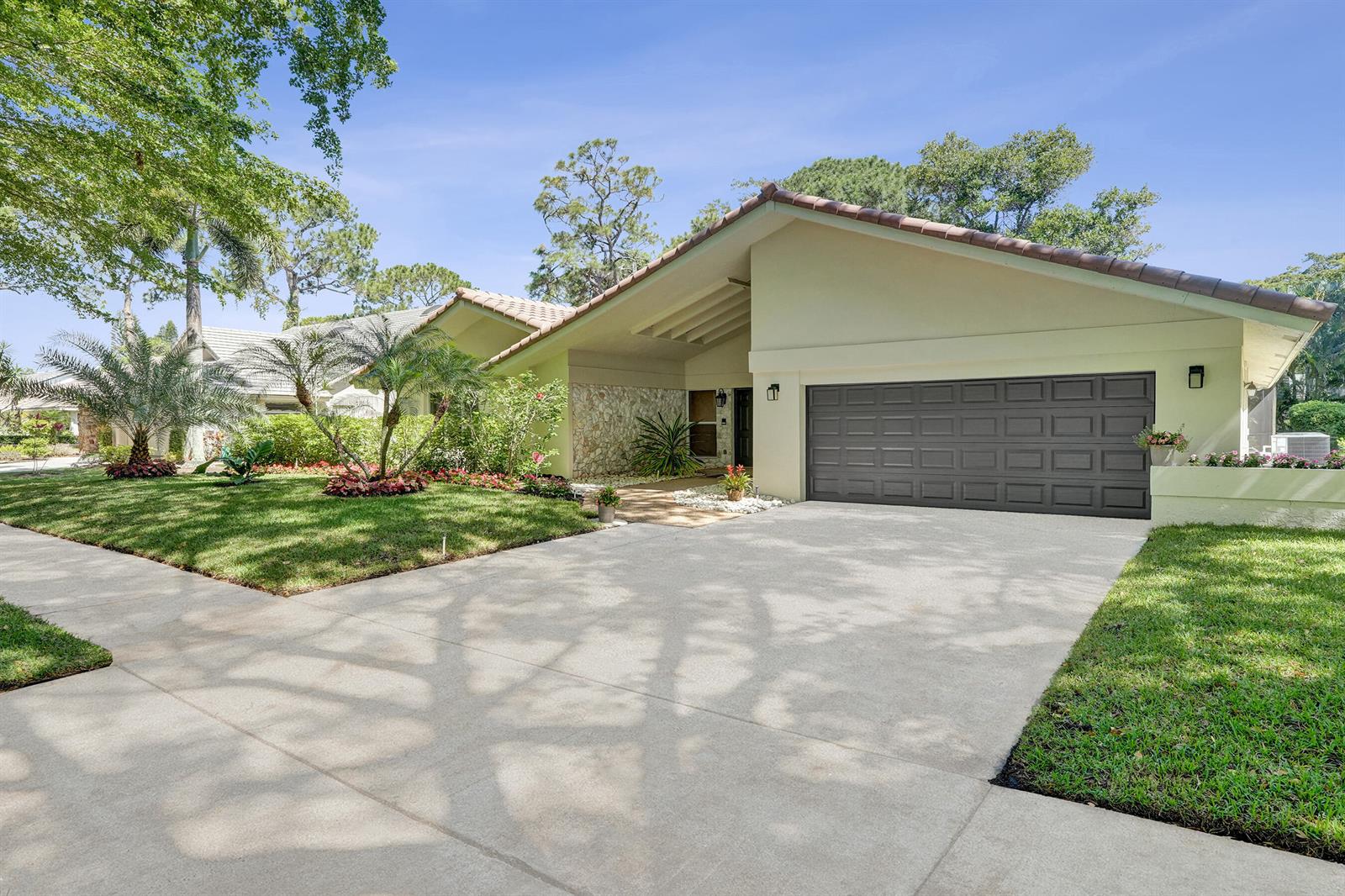 A single-story house with a beige exterior, stone accent wall, and a dark garage door — 2401 NW 39th Street, Boca Raton FL 33431, BOCA RATON, FL